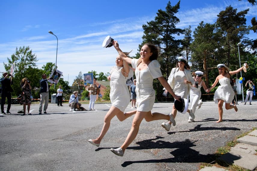 Why are Swedish teens in white hats singing and drinking on trucks?