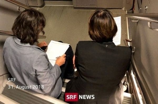 Swiss transport minister snapped sitting on steps of crowded train