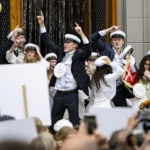Why are Swedish teens in white hats singing and drinking on trucks?