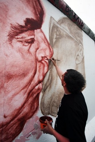 Russian artist Dmitry Vrubel recreating his original painting, “Brother Kiss.” Photo: DPA