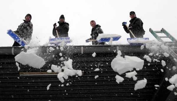 Men sweep a Lüdenscheid roof clean of snow.Photo: DPA