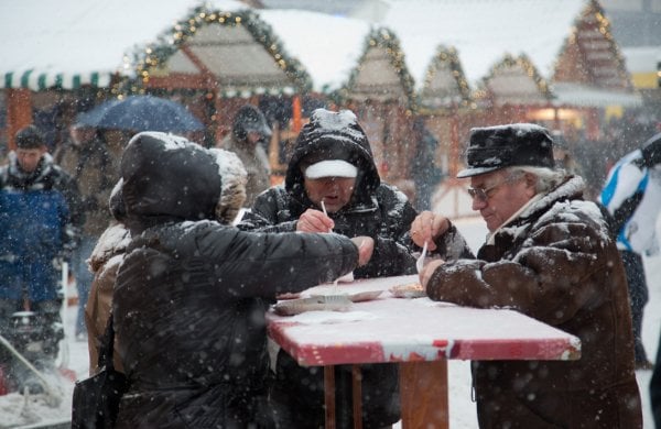 Berlin was hit by heavy snowfall over the weekend. But Christmas shoppers were undeterred. This group warm up with some traditional Berlin curried sausage at a Christmas marketPhoto: DPA