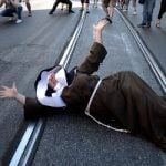 A demonstrator dressed as a nun shouts as she lies on the ground. Photo: Filippo Monteforte/AFP
