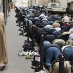 Praying in the street at the Goute d'OrPhoto: Martin Parr
