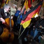 A cellist plays in front of 'Dügida' demonstrators in Düsseldorf. Some 5,000 people came out to protest against the anti-Islam movement there.Photo: DPA