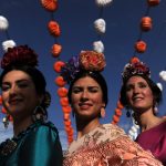 Three women wearing traditional Sevillana dresses.Photo: Cristina Quicler / AFP