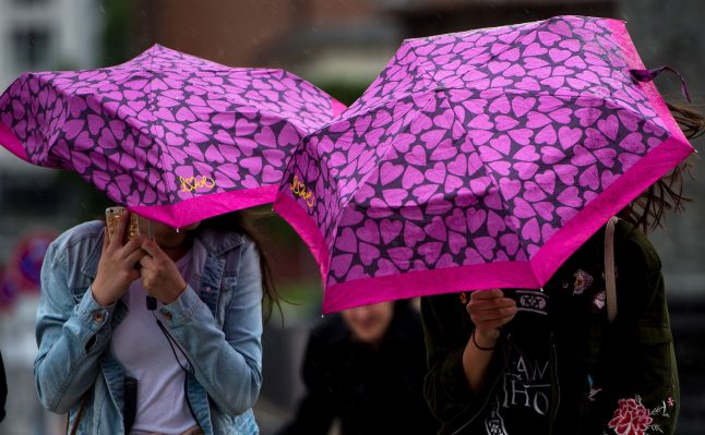 Two pedestrians attempt to protect themselves from the rain in Berlin