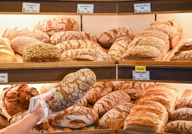 An employee selects a loaf of bread in a German bakery.