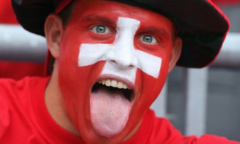A person with their face painted in the Swiss flag. 