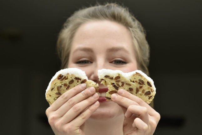 A woman holds a slice of Stollen bread. 