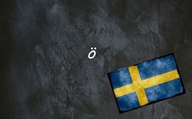 The letter ö written on a blackboard next to the swedish flag