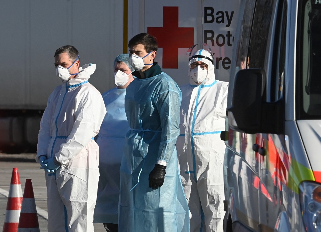 Men in protective clothes stand next to a mobile COVID-19 test station next to the border crossing between Austria and Germany AFP CHRISTOF STACHE