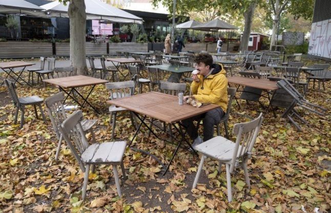 A man eats a sandwich in a Schanigarten