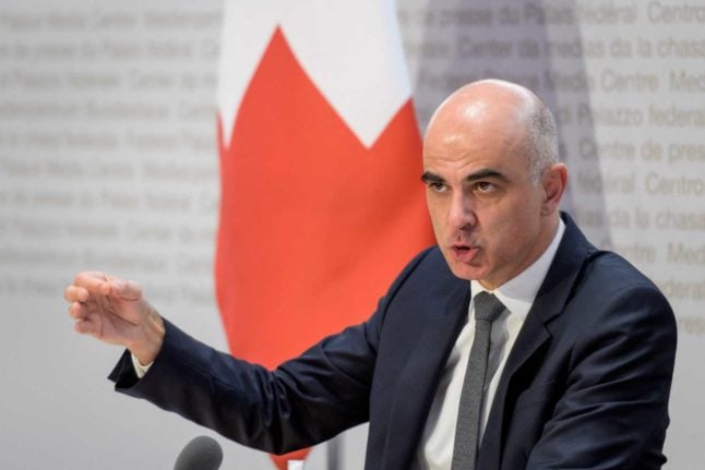 Swiss health minister Alain Berset speaks in front of a Swiss flag