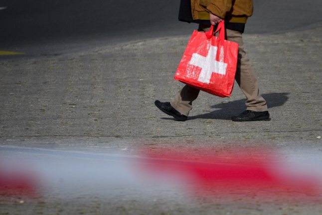 A man holding a supermarket bag bearing the Swiss cross walks across a square on September 21, 2012 in downtown Lausanne.