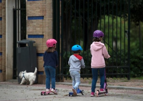 Children scoot near a park (Photo by CRISTINA QUICLER / AFP)