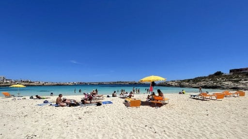 People sit on a beach in Lampedusa, Italy.