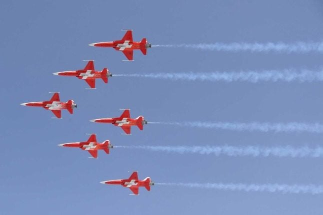 Fighter jets career through the sky in Swiss flag colours