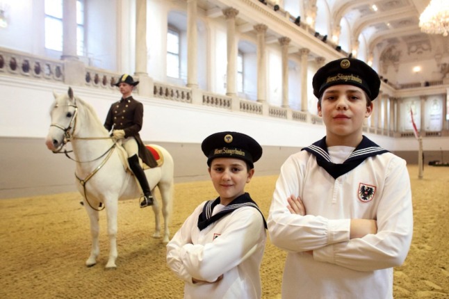 Two members of the Vienna Boy Choir pose with an Lippizaner horse of the Spanish Riding School. (Photo by DIETER NAGL / AFP)