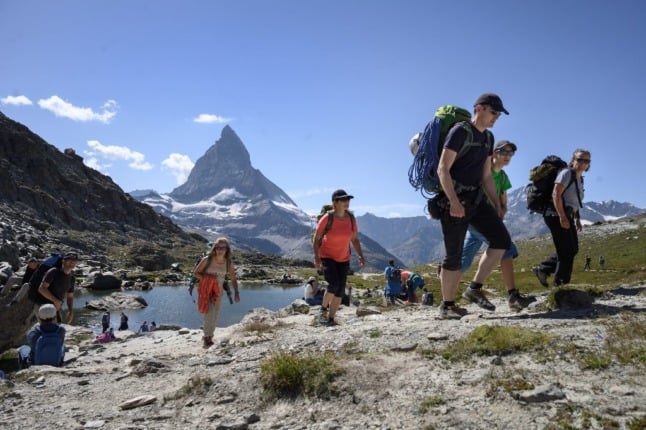Tourist wearing protective face masks stand with the Matterhorn mountain in background at the Gornergrat rocky ridge, 3'089 meter hight, above the resort of Zermatt as heatwave sweeps across Europe on August 8, 2020. (Photo by Fabrice COFFRINI / AFP)
