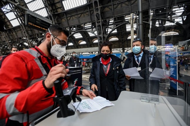 An Italian train station worker scans a green pass