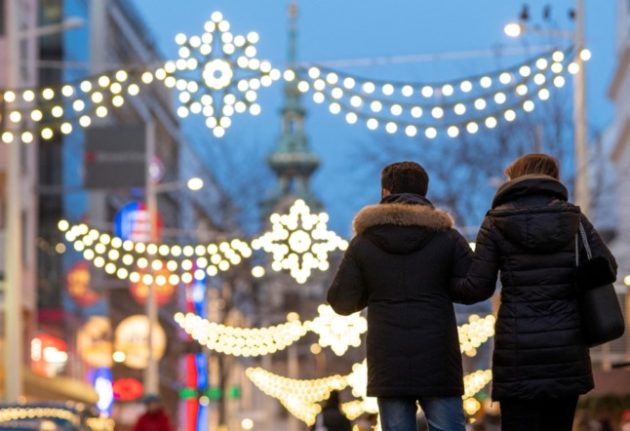 People walk during the twilight at Vienna's famous shopping Mariahilfer street decorated with Christmas lights on December 18, 2019 in Vienna, Austria. (Photo by JOE KLAMAR / AFP)