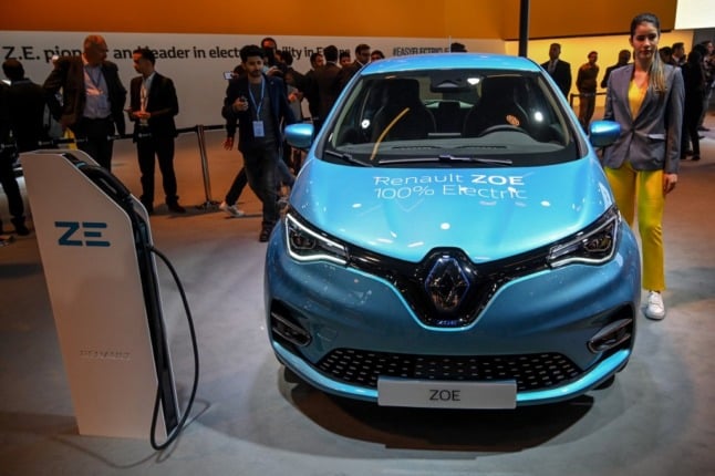 A light blue Renault Zoe electric car shown front-on at a motor show display stand