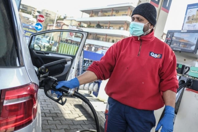 A station attendant fills a car with petrol.