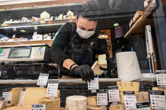 A woman sets up her display stand in a cheese store in Montpellier. Raclette cheese is being sold earlier every year.