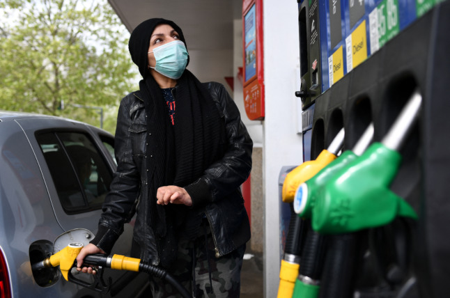 A woman fills her vehicle at a filling station in Paris. You don't have to own a car to qualify for France's new fuel subsidy.