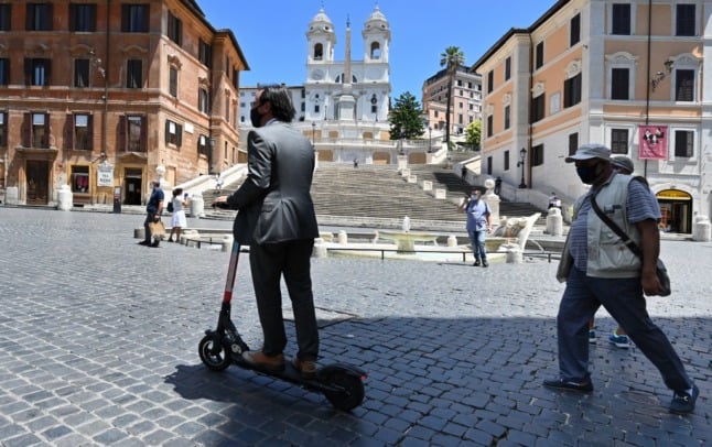 A man rides an electric scooter through Rome, Italy.