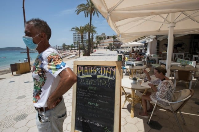 A waiter waits for customers at a restaurant near Playa de Figueretas in Ibiza on July 30, 2020. - There is no second wave of the coronavirus pandemic in Spain despite a fresh surge in infections in the country, a top health ministry official said. The pandemic has dealt a major blow to Spain's key tourism sector, which accounts for about 12 percent of its economy. (Photo by JAIME REINA / AFP)