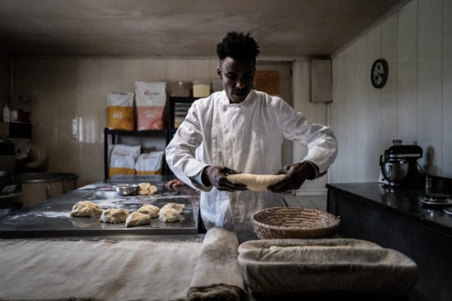 Guinean migrant Mamadou Yaya Bah prepares bread in the bakery where he works in the Ain department. Authorities reversed his order to leave France after his boss Patricia Hyvernet undertook a hunger strike.