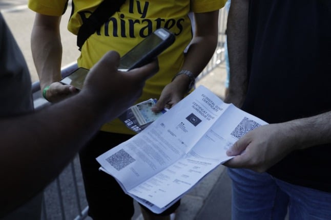 A spectator shows his health pass certificate prior to the start of a football match in Paris.