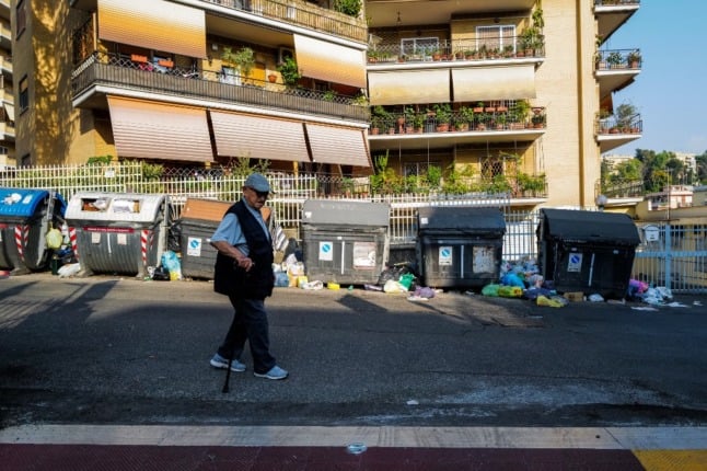 A resident walks past uncollected trash in Rome.