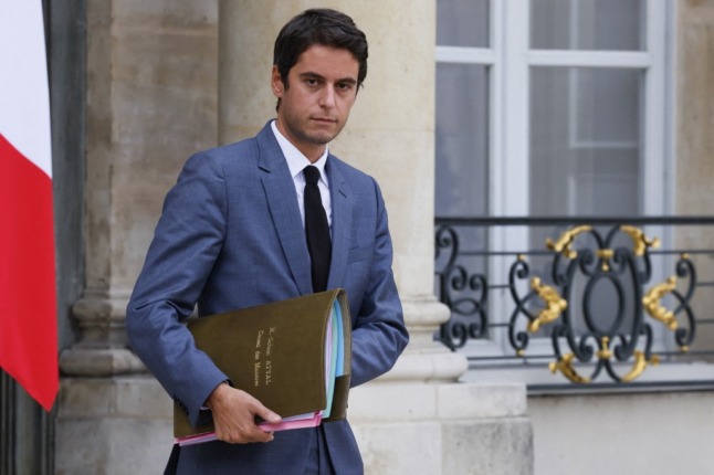 French government spokesperson Gabriel Attal walks out of the Elysee Palace, holding a large folder