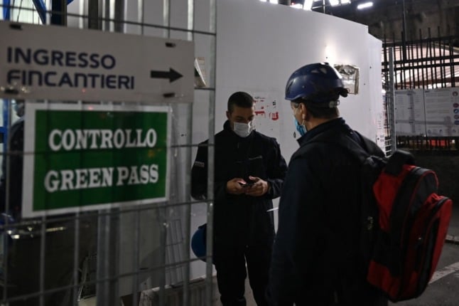 Workers in Italy show a green pass at the gate.