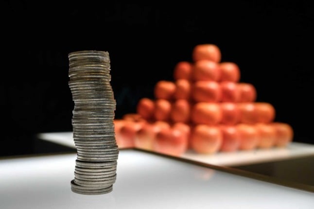 A pile of Swiss francs next to a stack of red apples. 