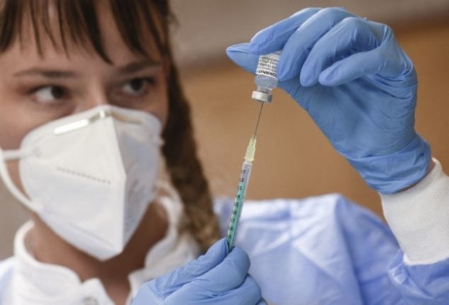 a nurse prepares to administer a Covid-19 booster vaccine