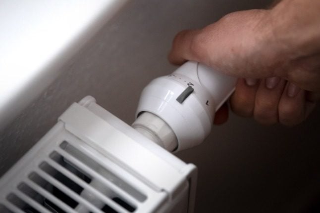 A man adjusts the thermostat on his radiator