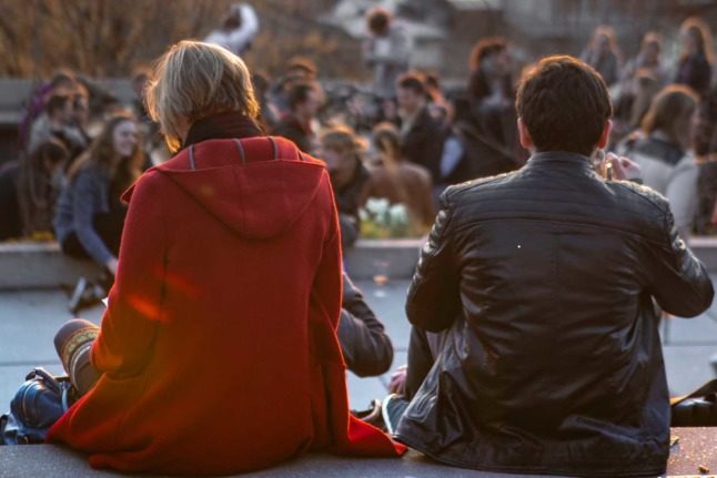 People sit in a square in Zurich at sundown 