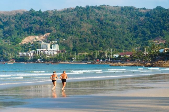 two retirees jog on a beach in the morning