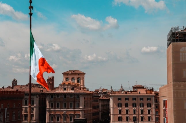 The Italian flag flies above a historic city centre.