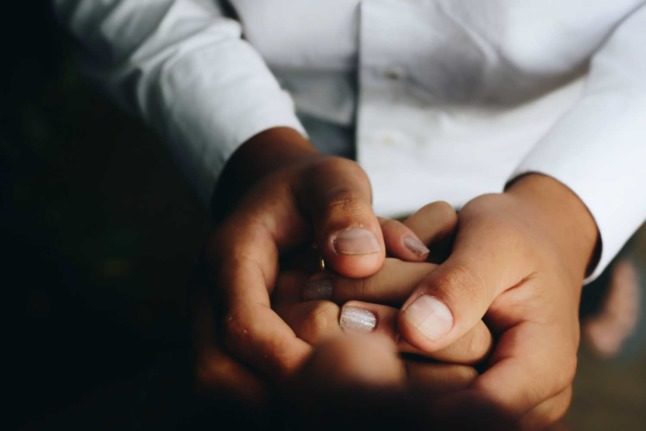 A person in a medical coat holds hands with another