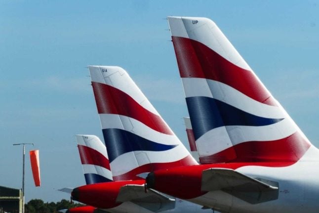 The colourful tails of several British Airlines aeroplanes at an airport. 