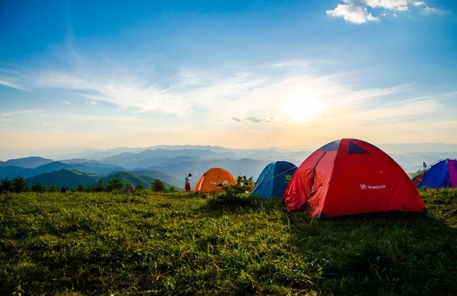 Camping tents in sunny grassy hills
