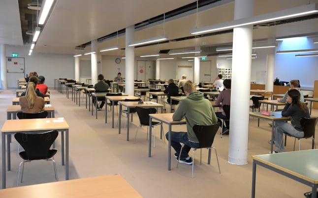 people sitting at desks at a classroom, about to take the swedish scholastic aptitude test