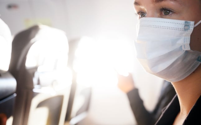 A woman wearing a face mask on a plane.