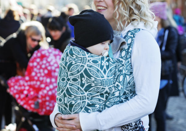 a woman carrying a baby in a woven wrap