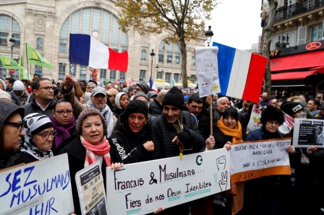 A large group of people in a crowd, including some in hijabs, protesting against Islamophobia in France